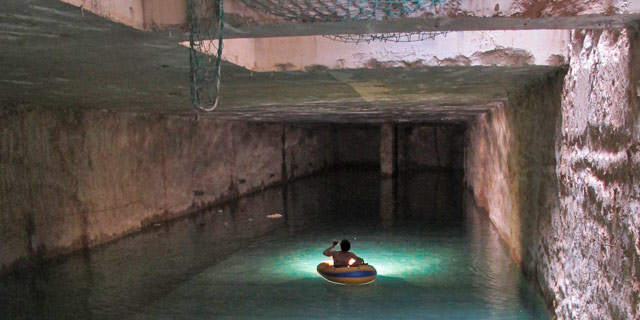 Un joven explora en balsa los túneles inundados del metro. | Enrique Escandell [MÁS FOTOS]