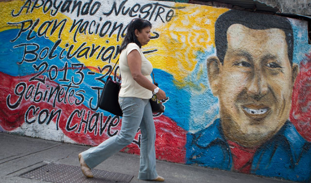 Una mujer camina delante de una pintura de apoyo a Chvez en Caracas. | Efe