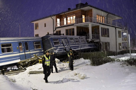 Policas suecos junto al tren empotrado en un bloque de viviendas. | Reuters