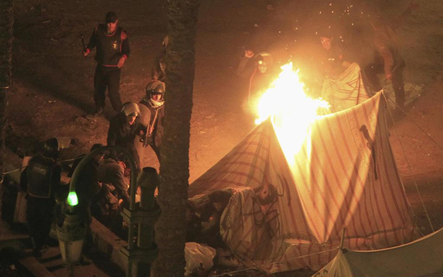 Un opositor del presidente Mursi escapa de su tienda en llamas en la Palza Tahrir. | Reuters