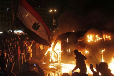 Manifestantes frente a un vehculo en llamas de las fuerzas de seguridad en El Cairo. | Efe