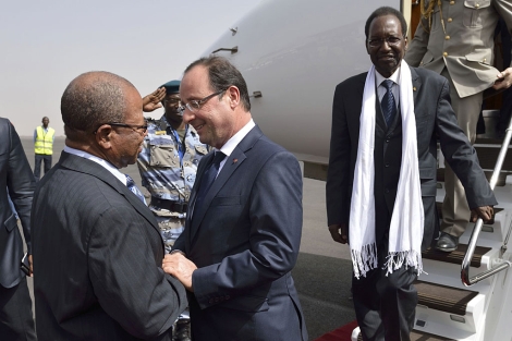 El presidente francés Hollande intercambia palabras con el presidente interino de Mali, Dioncounda Traoré, entre el séquito que le esperaba en el aeropuerto a su llegada a Mali. | Afp