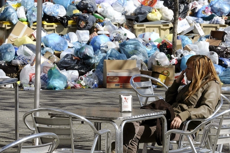 Una joven sentada en una terraza junto a un montn de basura. | Efe
