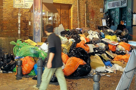 Un ciudadano pasa por delante de una montaa de basura, en Granada. | Jess G. Hinchado