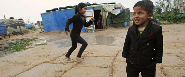 Dos pequeos refugiados sirios juegan en un campamento de la ciudad libanesa de Tiro. | Reuters