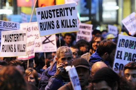 Varios asistentes muestran pancartas contra la austeridad. | Afp