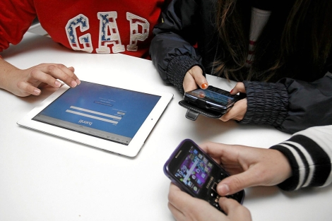 Jvenes utilizando una tableta y telfonos mviles. | Roberto Prez