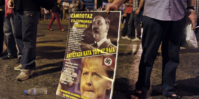 Un hombre muestra un cartel que compara Hitler con Merkel en Atenas. | Afp
