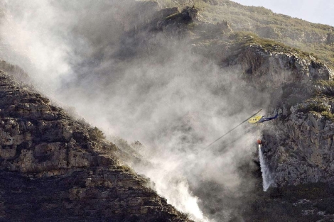 Un helicptero trabaja este lunes en las tareas de extincin del fuego en Barx. | Efe