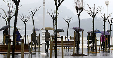 Paseantes se protegen de la lluvia en San Sebastin. | Juan Herrero / Efe