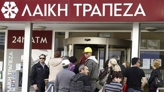 Varias personas hacen cola a las puertas de una sucursal del Banco Laiki en Nicosia. | Efe