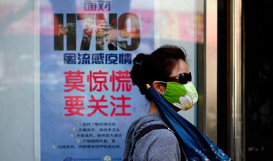 Una china con mascarilla delante de un cartel sobre el H7N9.| Afp