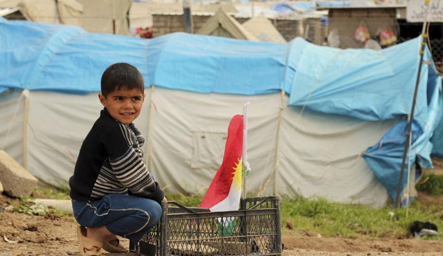 Un nio sirio juega con una bandera del Kurdistn, en el campo de refugiados de Domiz. | Efe