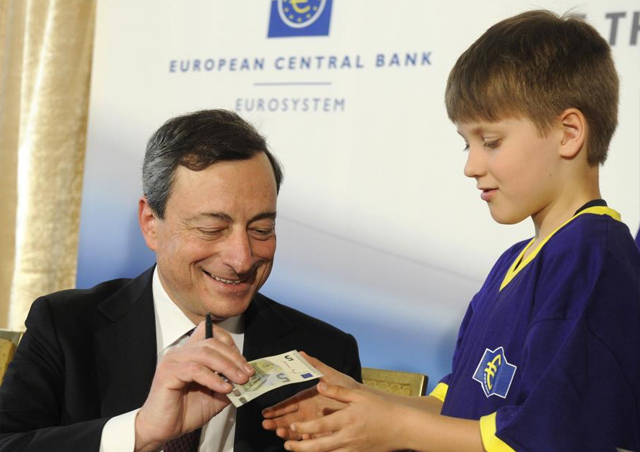 Draghi enseña el nuevo billete de cinco euros a un niño. |Reuters