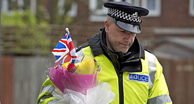 Un polica, con flores y una bandera en recuerdo del soldado Rigby. | Reuters
