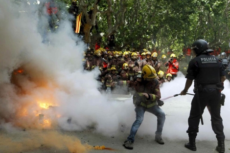 Un bombero trata de evitar que un 'mosso' apague el fuego ante el Parlament. | Efe