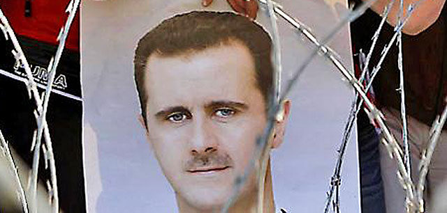 Manifestantes con una foto del presidente de Siria. | Reuters