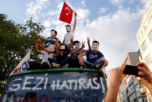 Manifestantes, con las caretas de Anonymous, de la Plaza Taskim de Estambul., hacen el signo de la victoria con sus dedos. | Reuters