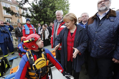 La canciller alemana conversa con uno de los rescatadores acuticos en Passau. | Reuters