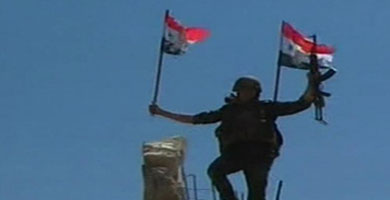 Un soldado sirio con una bandera del pas, en Quseir.| Reuters