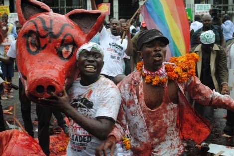 Manifestantes de Kenia manchados de sangre sostiene la cabeza de un cerdo de cartón.| X. F.C.
