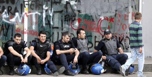 Policas turcos antidisturbios delante de una sucursal bancaria daada en la plaza Taksim. | Efe