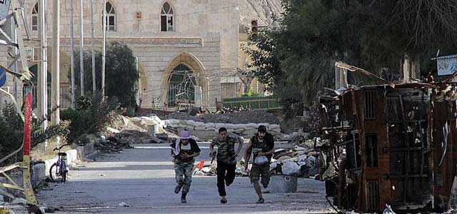 Tres rebeldes sirios corren en la localidad de Deir al Zor. | Reuters