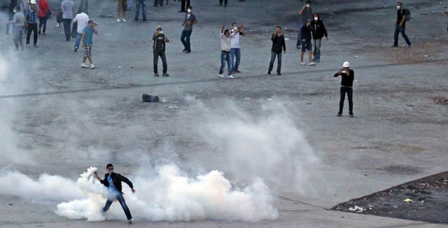 Un manifestante lanza de vuelta una lata de gas lacrimgeno. | Reuters