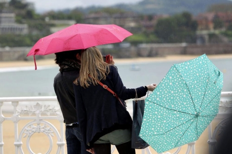 Dos mujeres con paraguas y chaqueta el 19 de junio en la playa de San Sebastin. | Efe