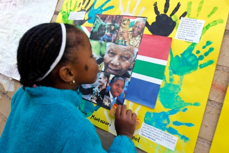 Una nia besa una foto de Mandela en un mural a la entrada del hospital de Pretoria.| Efe