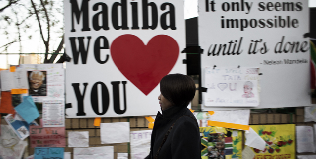 Una mujer pasa delante de la pared en la que se han colgado los mensajes de nimo a Mandela. | Afp