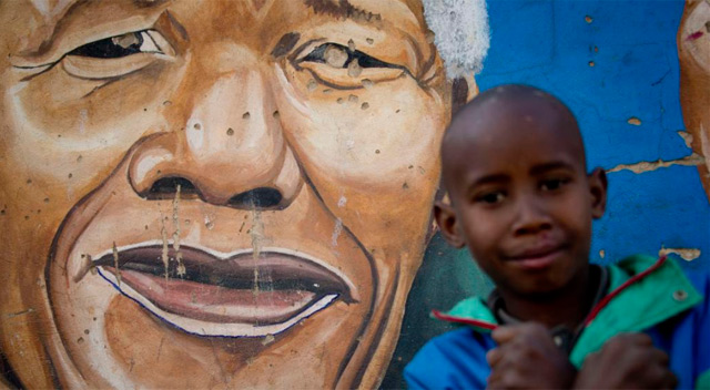 Un nio frente a una pintura con la imagen de Madiba. | Afp