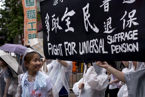 Una manifestante sonrie junto a un cartel que reivindica el sufragio universal.| Afp