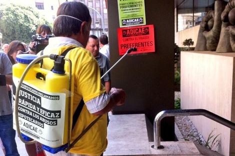 Un activista 'fumiga' los productos txicos en la sede de Bankia en Valencia. | @carlosbonastre