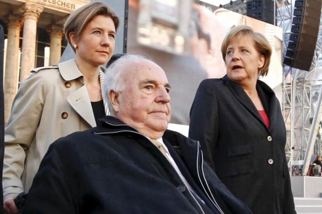 Kohl, en silla de ruedas, llevado por su mujer y acompaado por Merkel. | E.M.