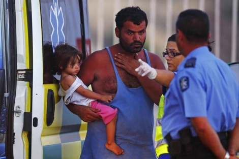 Dos policas malteses hablan con un inmigrante del barco y con su hija.| Reuters