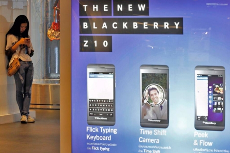 Una joven consulta su mvil junto a un anuncio de la nueva BlackBerry Z10. | Efe
