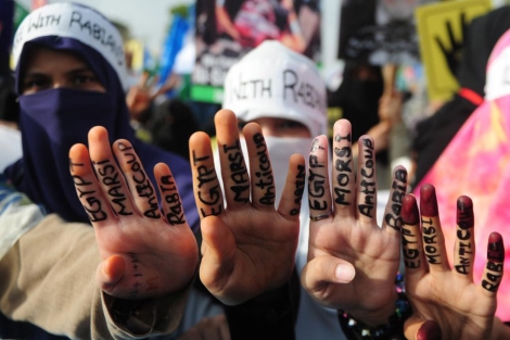 Varias egipcias muestran mensajes escritos en sus dedos en forma de protesta.| Afp