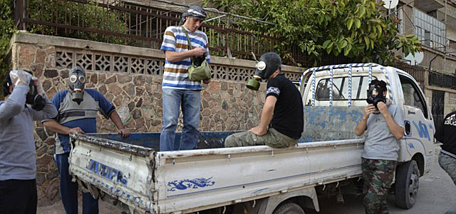 Activistas sirios con máscaras siguen buscando cadáveres. | Reuters