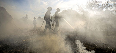 Dos operarios apagan el fuego declarado en Rianxo. | Brais Lorenzo / Efe