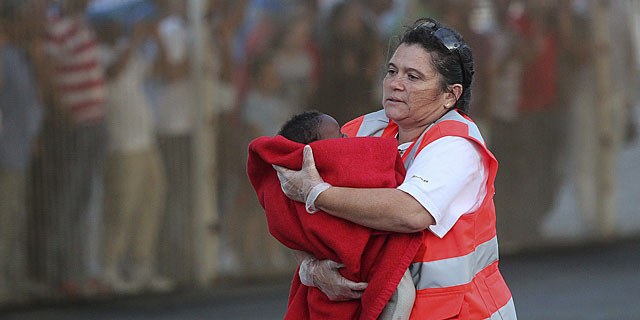 Personal de la Cruz Roja atiende a unos de los bebs que viajaban en la patera. Efe