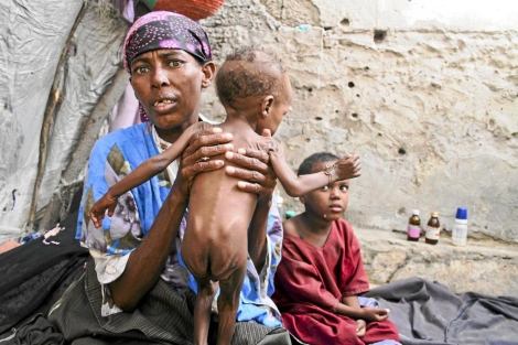 Una mujer sostiene a su hijo de dos aos en un centro de distribucin de urgencia somal | Efe