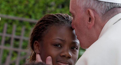 El Papa besa a una nia a su llegada al centro de Critas de Ass. | Efe