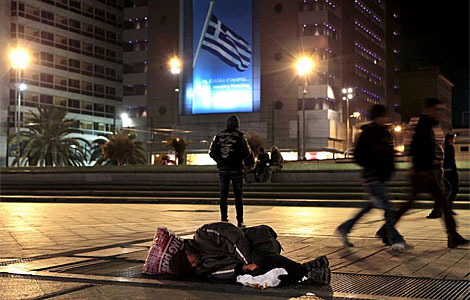Un hombre sin techo duerme en una céntrica plaza de Atenas.| Efe