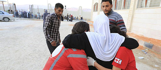 Trabajadores de la Cruz Roja ayudan a una mujer cerca de Damasco. | Efe