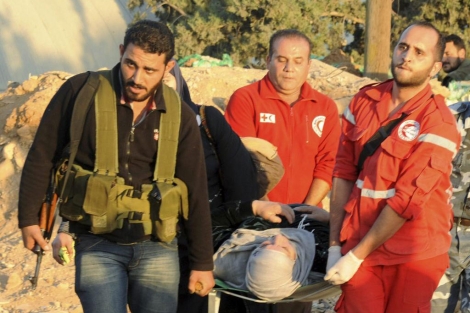Dos miembros de la Cruz Roja asisten a una mujer herida en Siria. | Ap
