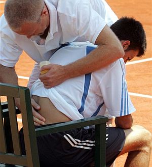 El 'fisio' del torneo atiende a Djokovic durante el segundo set. (Foto: AP)