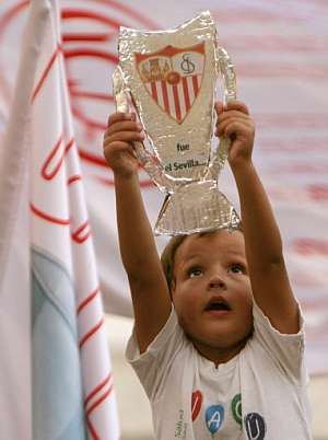 Un joven aficionado del Sevilla levanta una reproduccin en papel de la Supercopa de Europa. (Foto: AFP)