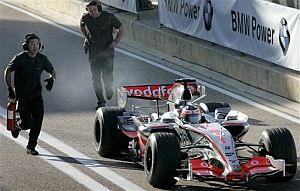 El coche de Alonso echa humo y un operario corre hacia l con un extintor. (Foto: AP)
