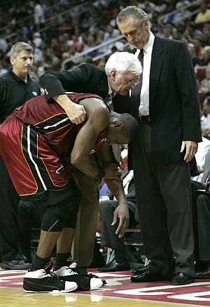 Dwayne Wade es ayudado por el médico del equipo y Pat Riley, tras sufrir la lesión. (Foto: AP)